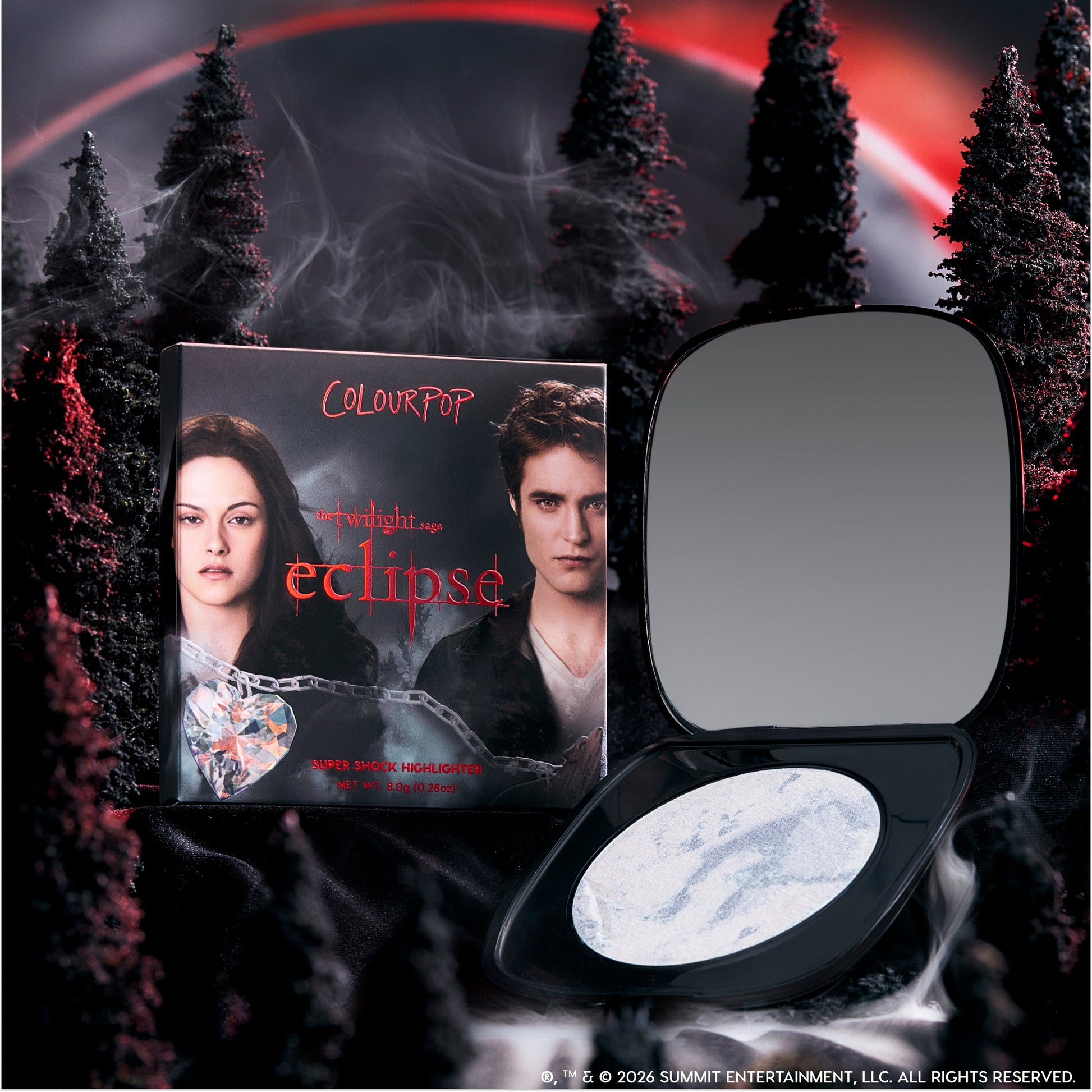 ColourPop Change Me Mega Highlighter compact lies open beside its Twilight Eclipse-themed box, featuring two characters, against a dark smoky forest and red eclipse sky for a dramatic, supernatural makeup product display.
