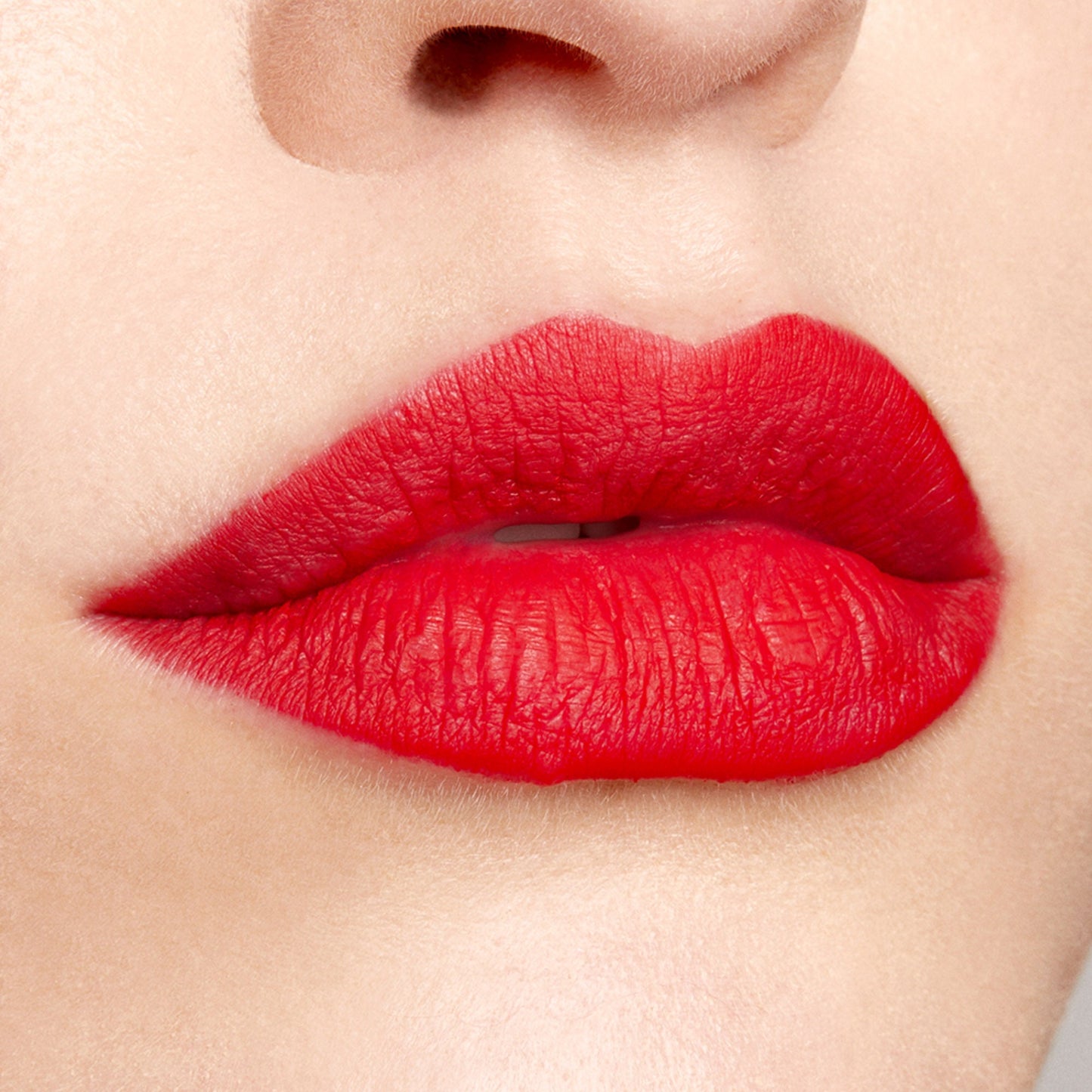 Bold red lips wear Bossy, a ColourPop Lippie Pencil, lining and filling the mouth with rich matte true red; crisp edges and full coverage shown in a close-up beauty shot against natural skin.